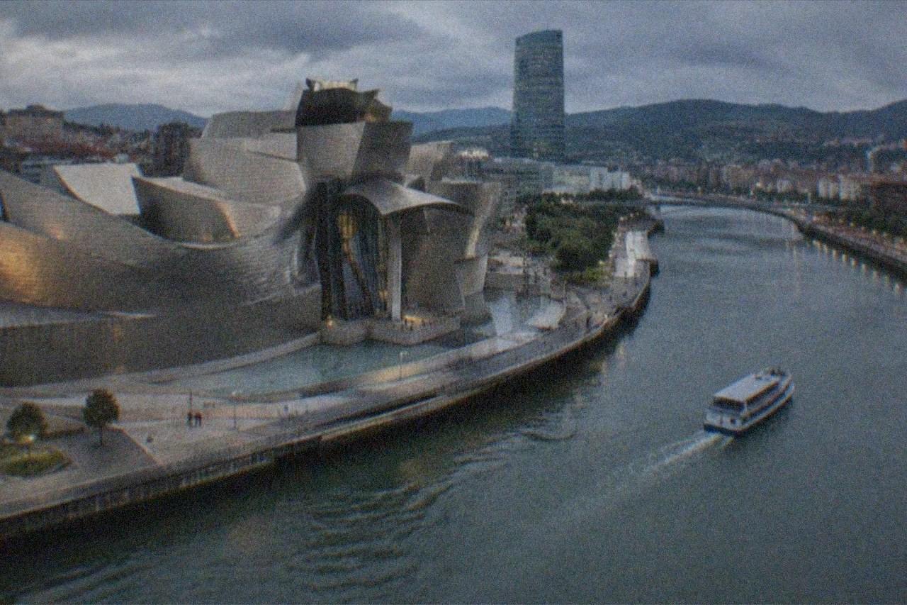The curved titanium exterior of the Guggenheim Museum Bilbao beside the Nervion estuary on a bright day