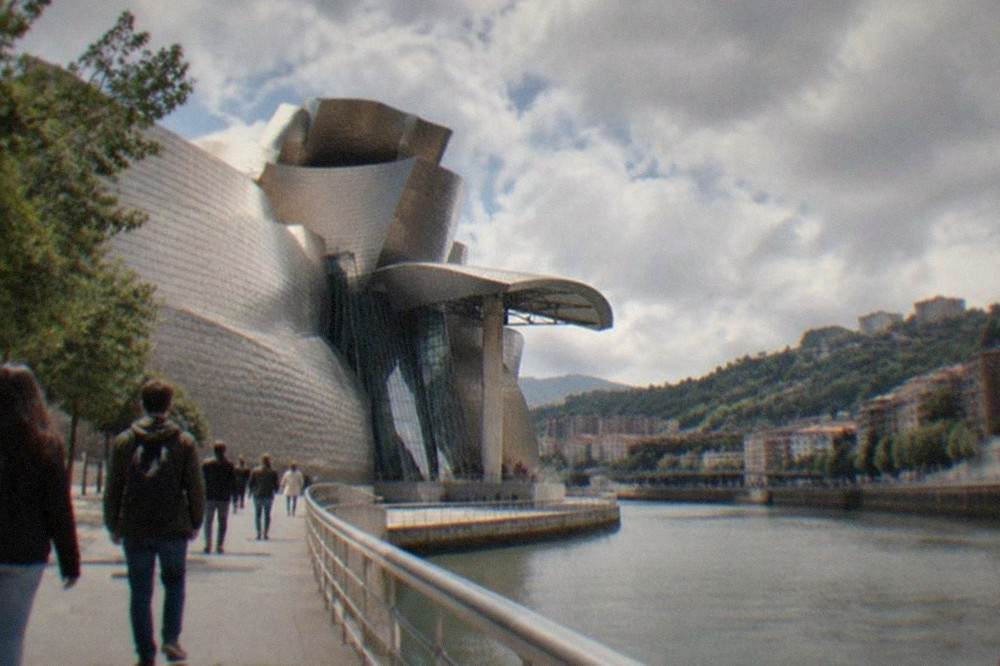 Visitors walking along the riverside promenade toward the Guggenheim Museum Bilbao