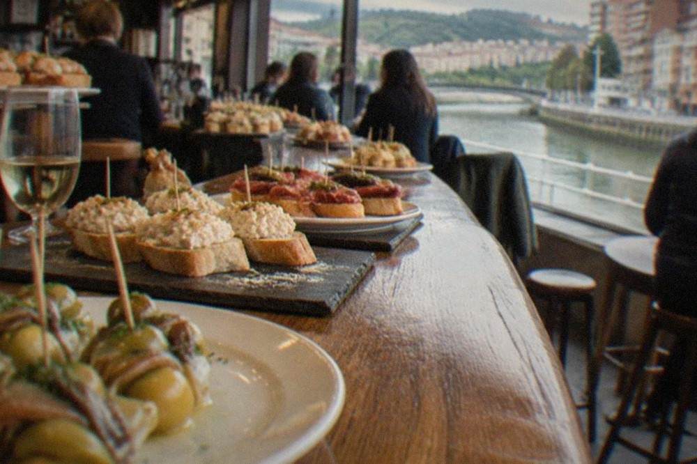 A crowded pintxos bar counter in Bilbao's old town with small plates on display