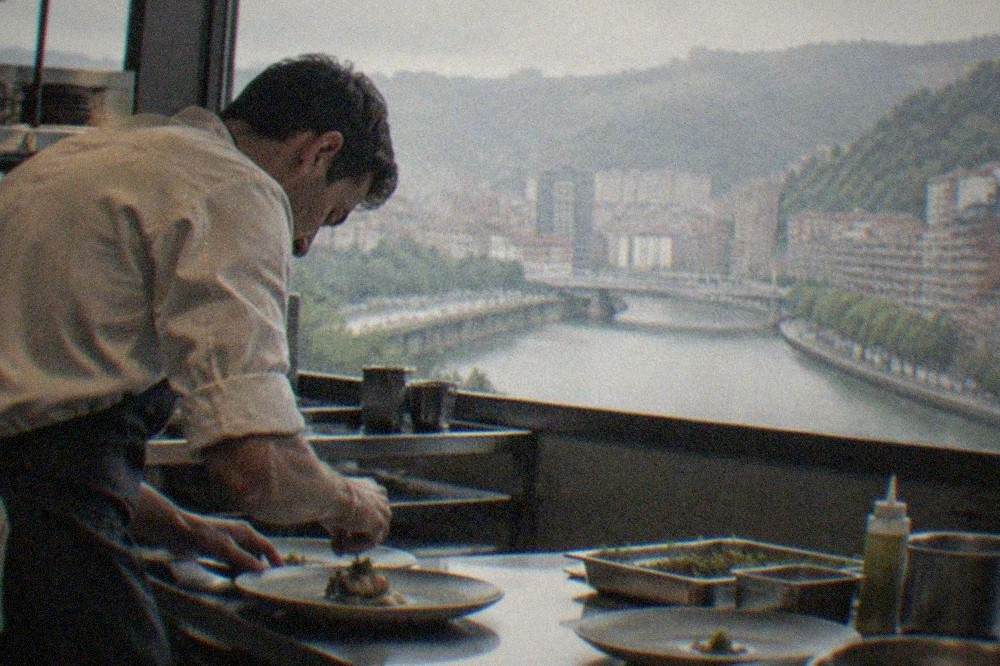 A chef plating a refined dish in a modern Bilbao restaurant kitchen