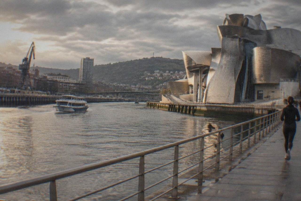 The titanium curved exterior of the Guggenheim Museum Bilbao beside the Nervion river on a bright day