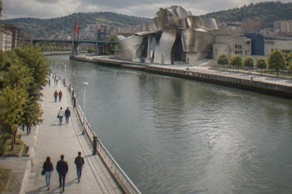 Visitors walking along the riverside promenade toward the Guggenheim Museum Bilbao entrance