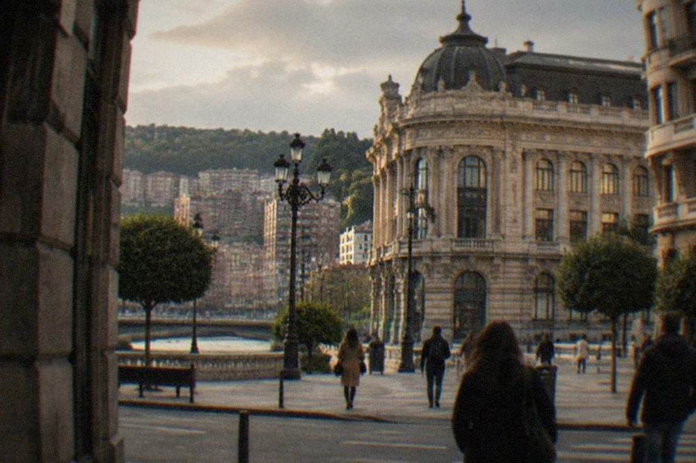 Plaza Moyúa in central Bilbao seen from a side street, with the Chavarri palace facade and pedestrians crossing