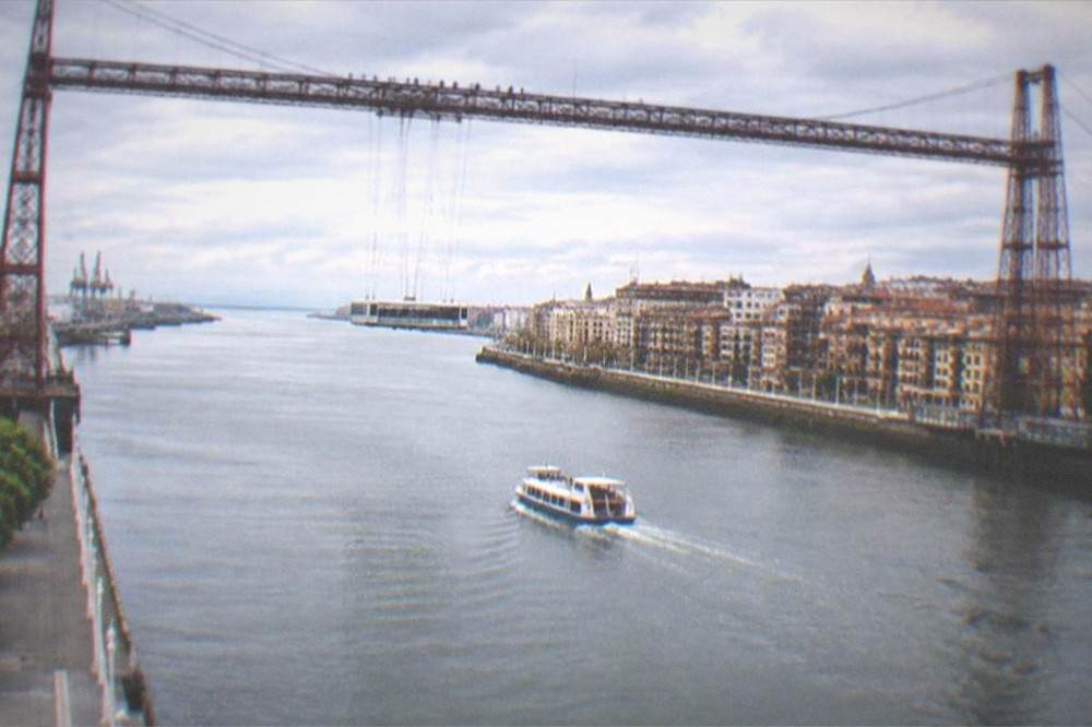 The Vizcaya transporter bridge over the Nervión estuary at Portugalete with its suspended gondola carriage and walkers on the upper walkway