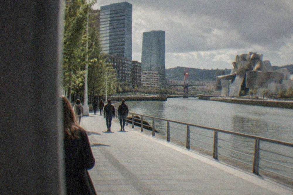 Walkers on the riverside promenade beside the estuary with the Guggenheim in the distance
