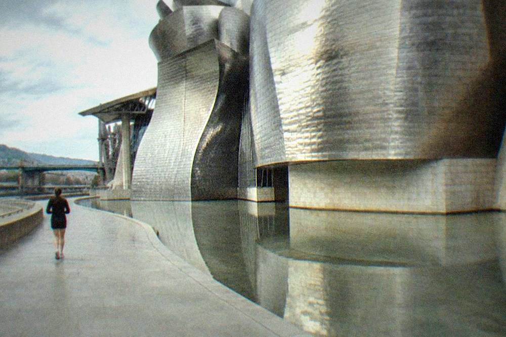The titanium curves of the Guggenheim Museum reflected in the shallow pool at its base