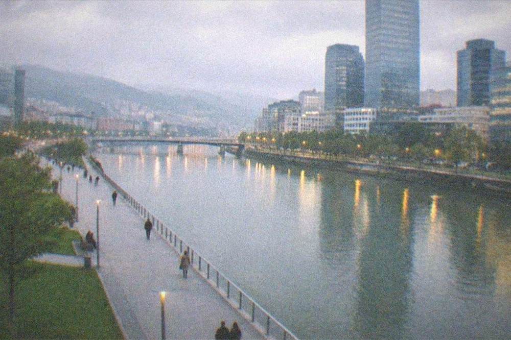 The riverfront promenade at dusk with the estuary and city lights reflected in the water