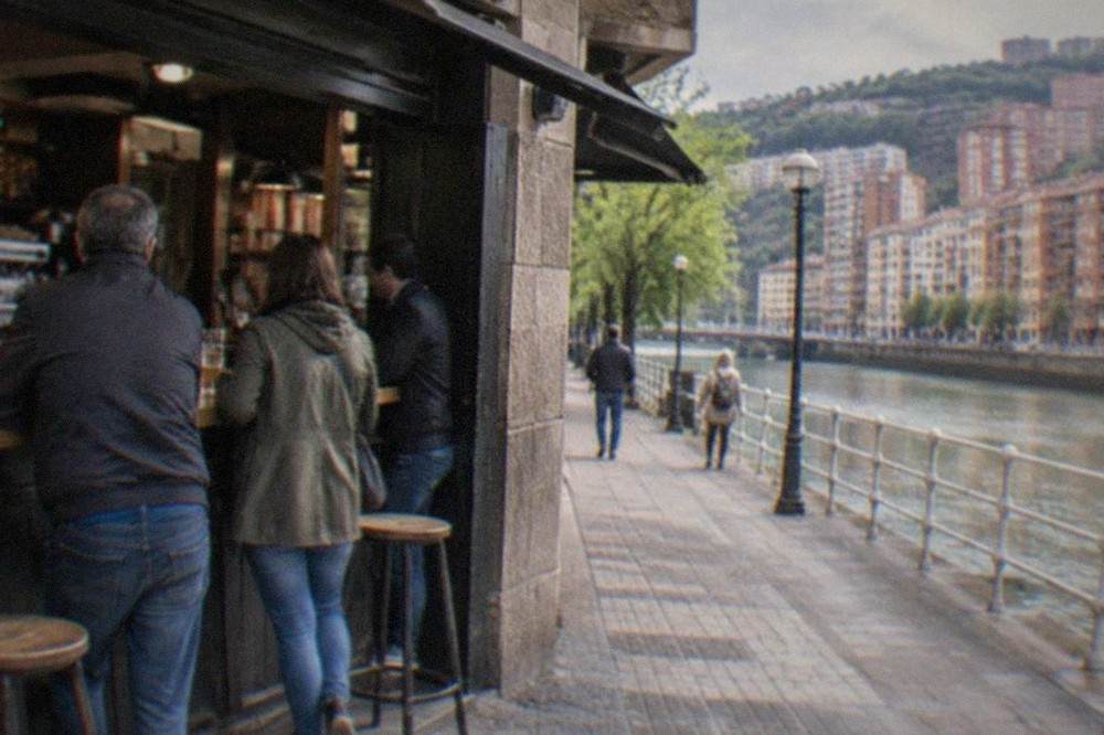 Morning light on a corner cafe in a residential Bilbao neighbourhood, with locals standing at the bar
