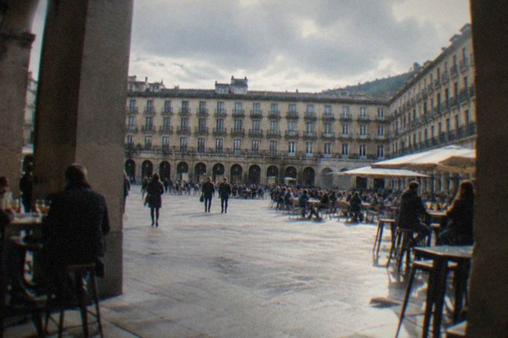 Arcaded facades of Plaza Nueva in Bilbao with people seated at outdoor pintxos bar tables