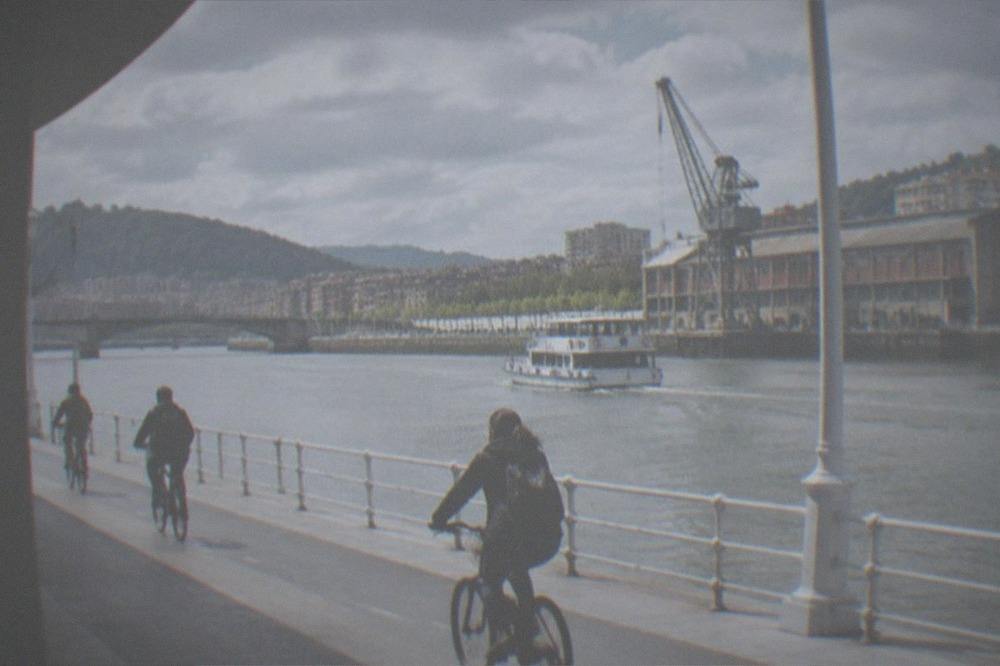 Cyclists riding along the flat riverside path beside the Nervion estuary in Bilbao