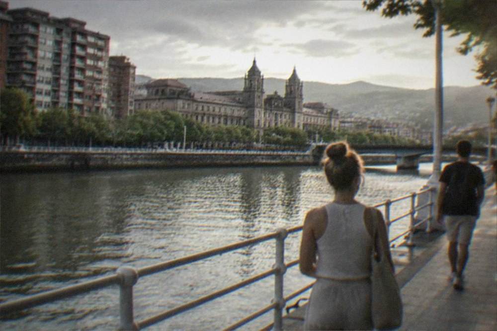 People walking along the riverside promenade in the Deusto area of Bilbao on a bright summer afternoon