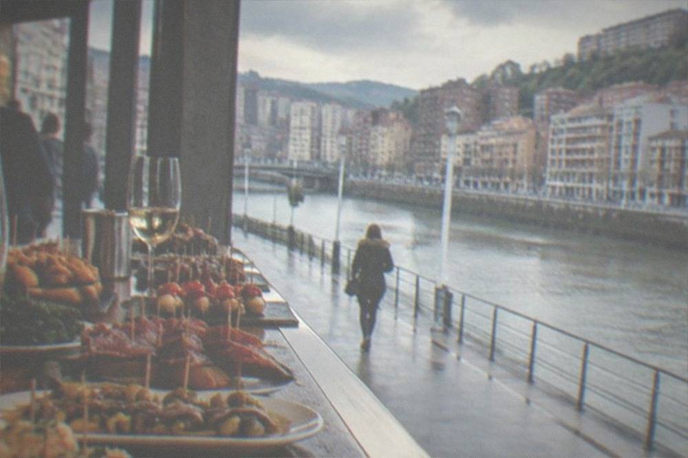 A pintxos bar counter in Bilbao loaded with small skewered bites and glasses of txakoli wine