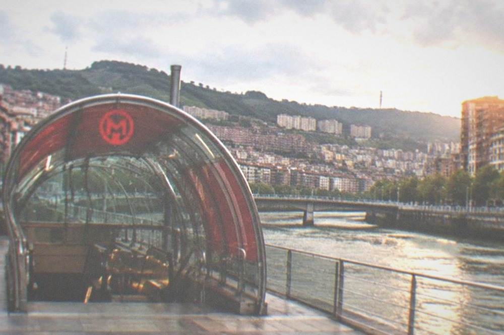 A Metro Bilbao station entrance with the network's red logo on a city street