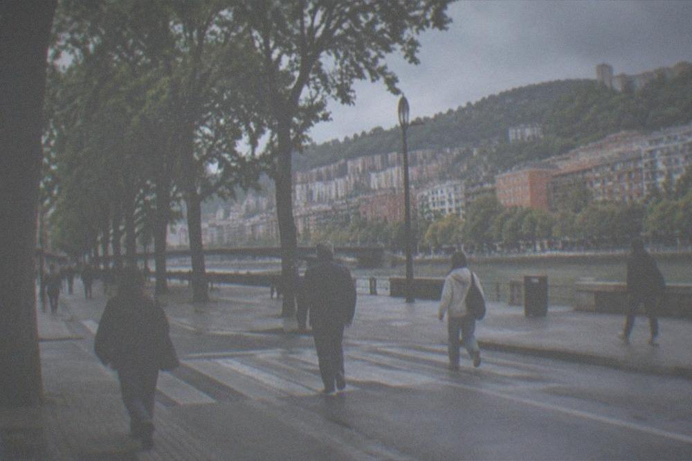 Pedestrians crossing a wide tree-lined street in central Bilbao near Moyua
