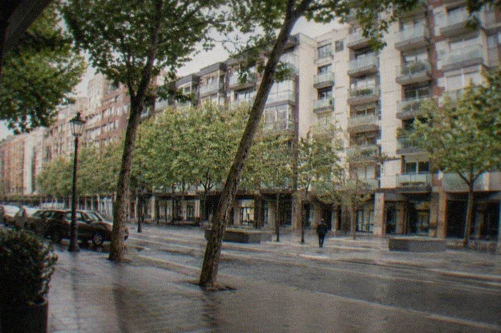 Apartment buildings with glass balconies on a wide street in Indautxu, Bilbao, under a grey sky