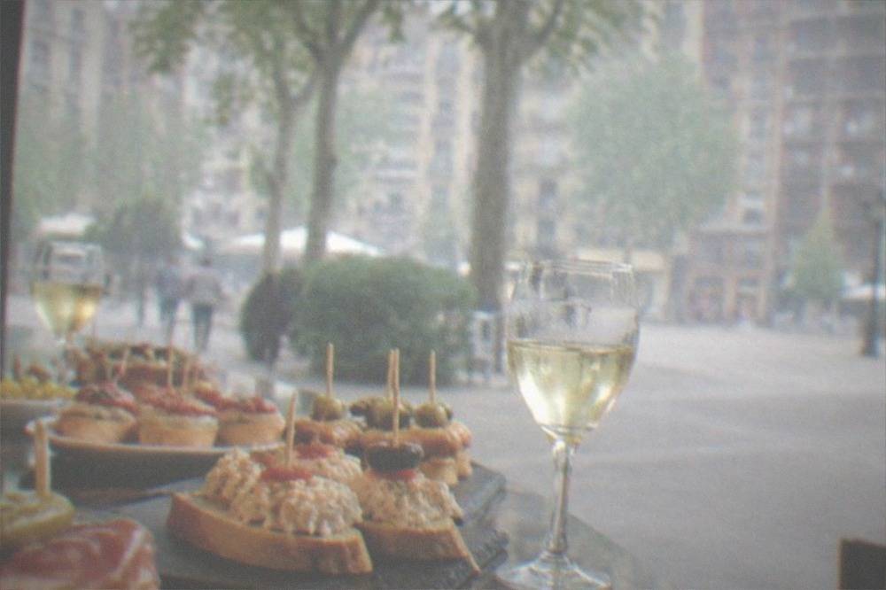 Close-up of pintxos arranged on a bar counter with toothpicks and small wine glasses