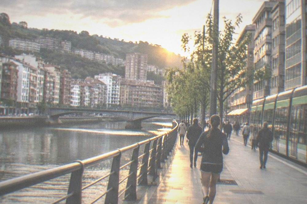 A Bilbao tram passing modern buildings on a street with pedestrians