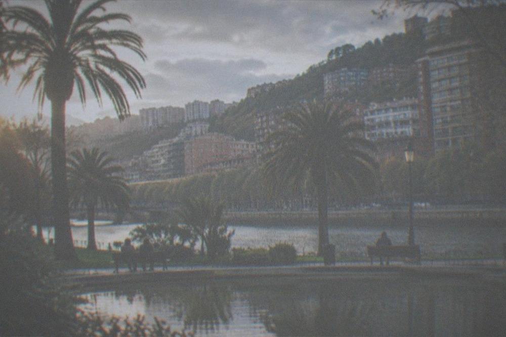 Doña Casilda park in Bilbao with a curved pond, palm trees and people on benches