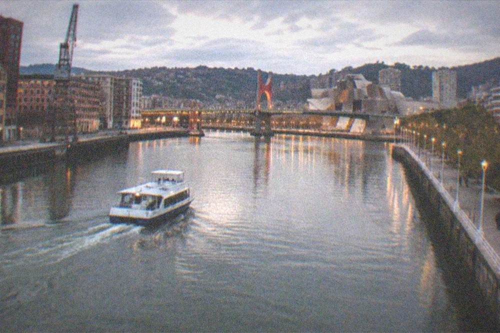 Evening view of illuminated bridges and buildings along the Nervion estuary in Bilbao