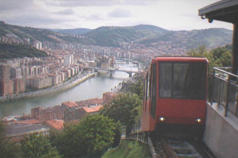A red funicular carriage arriving at the upper station terrace on Mount Artxanda above Bilbao