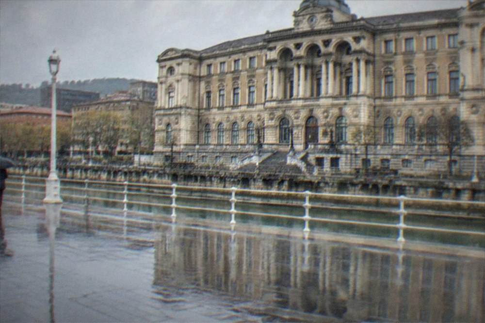 Rain-slicked Arenal promenade with the City Hall facade reflected in wet paving