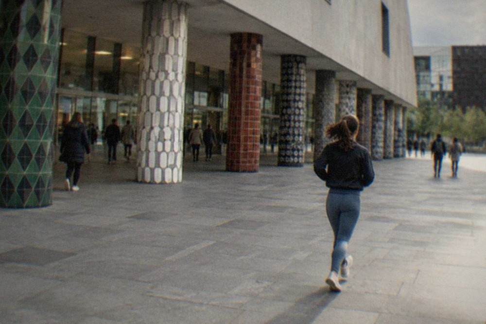 A bright indoor atrium with columns and people walking through a modern cultural centre