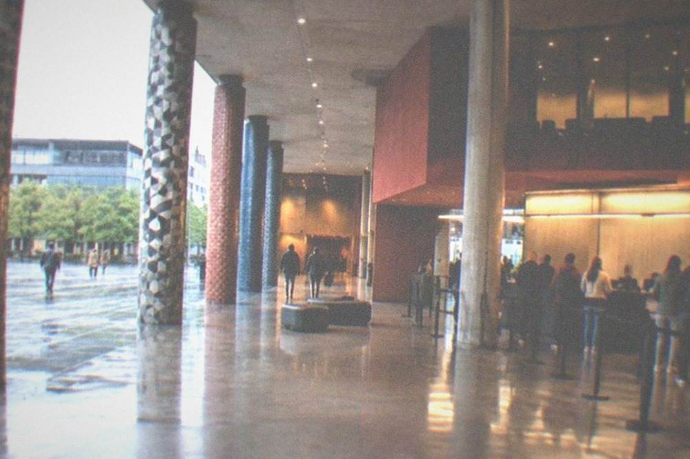 A ticket desk and lobby area inside a modern cultural centre with visitors queuing