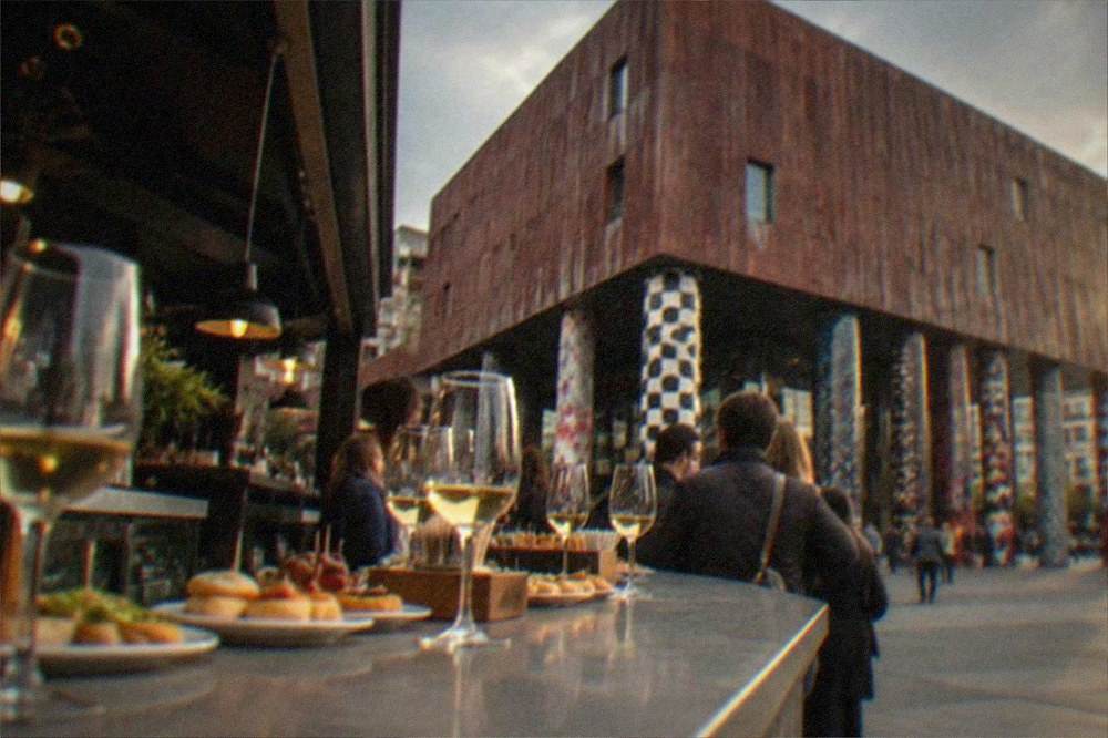 A busy pintxos bar counter with plates of small snacks and glasses of txakoli wine