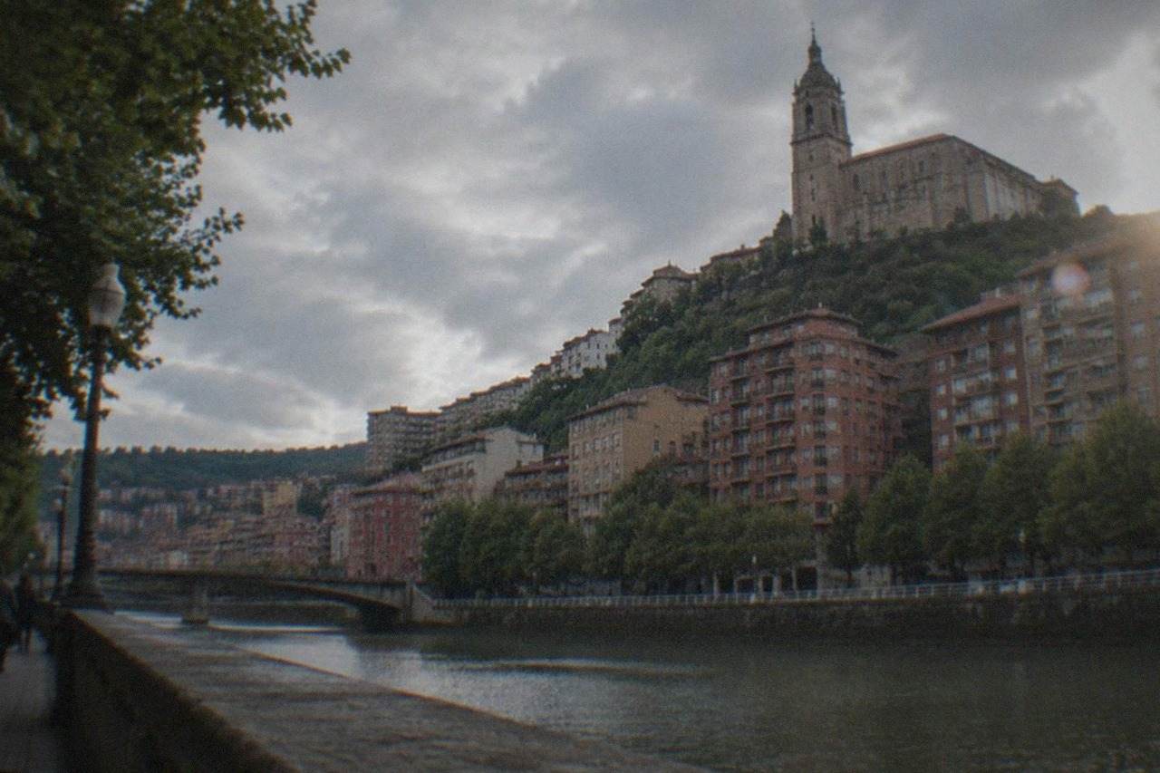 A hilltop basilica with a tall bell tower rising above rooftops in Bilbao, Spain