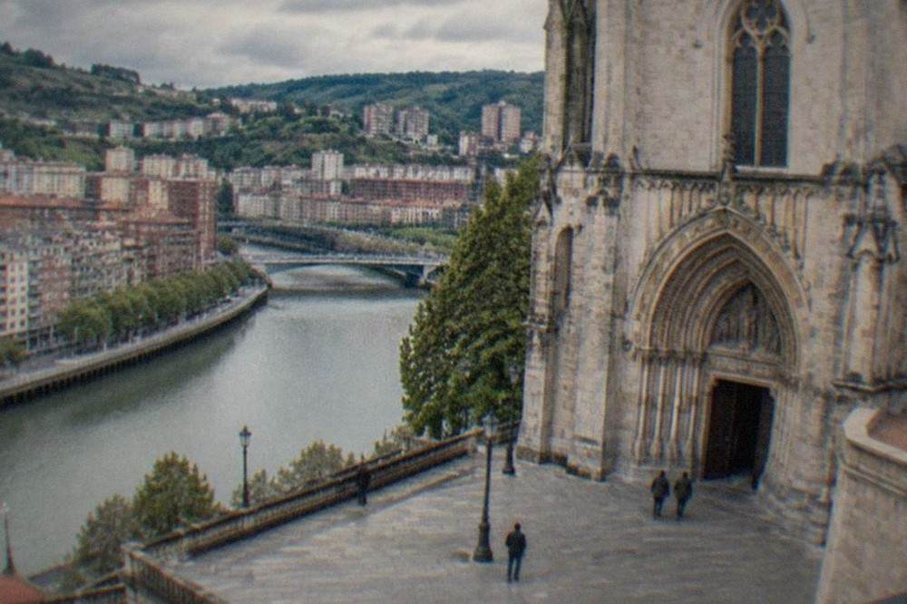 The stone facade and arched entrance of a basilica in Bilbao seen from the esplanade