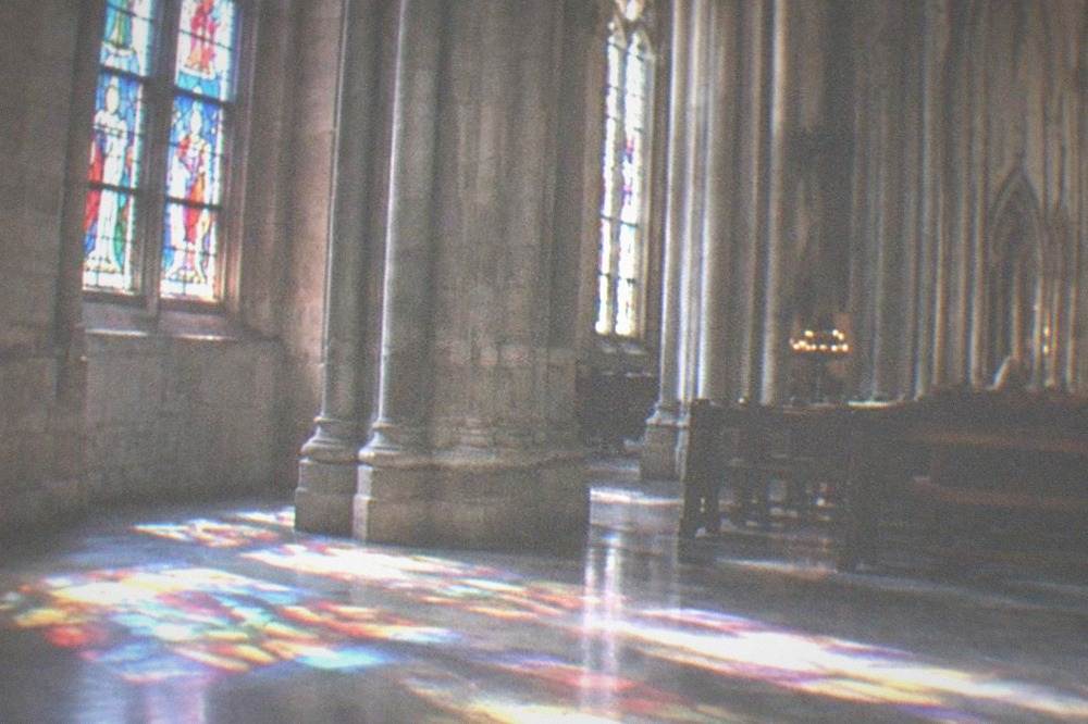 Sunlight falling through stained glass onto the stone floor of a church interior in Bilbao