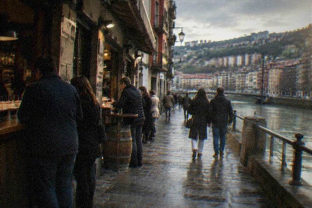 People walking through narrow old town streets with pintxos bars in Bilbao, Spain