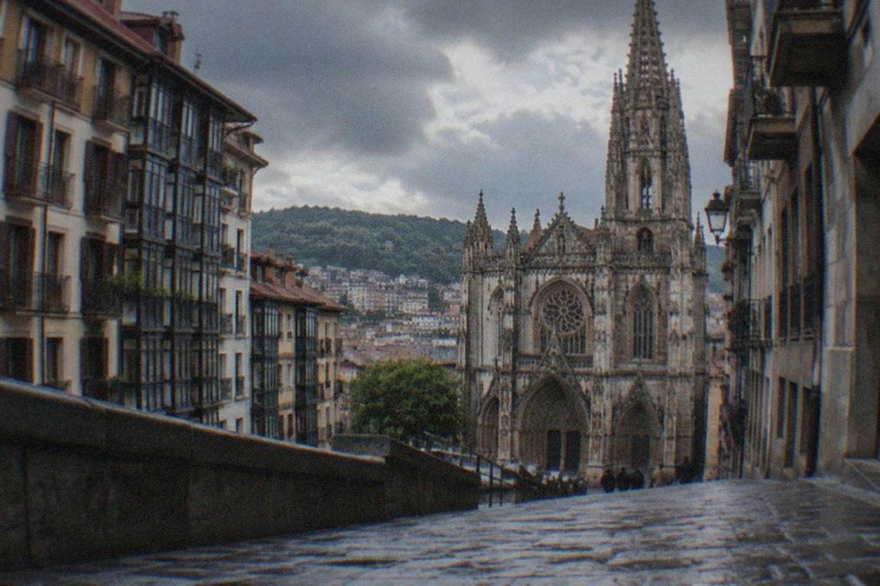 Gothic cathedral facade rising above a narrow old town street in Bilbao on a cloudy day