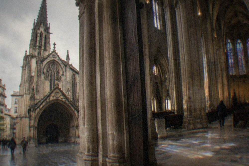 Interior of a Gothic cathedral with tall stone columns and stained glass light falling on the nave floor