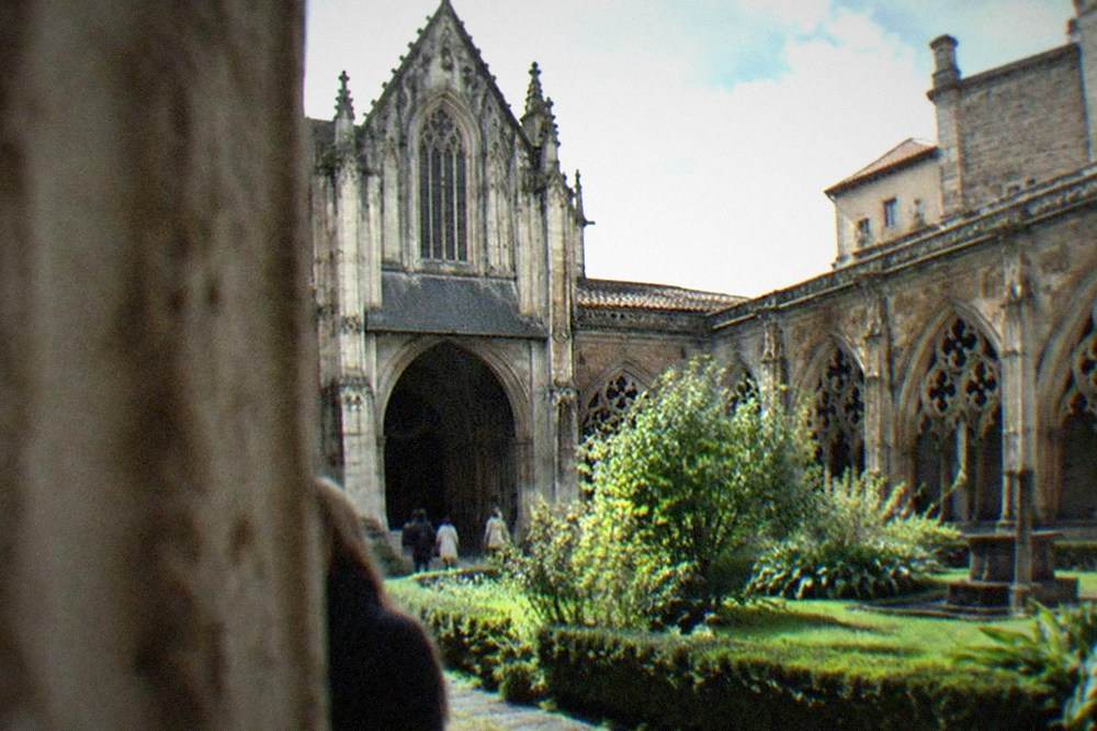 Stone cloister with gothic arches surrounding a small green garden in a cathedral