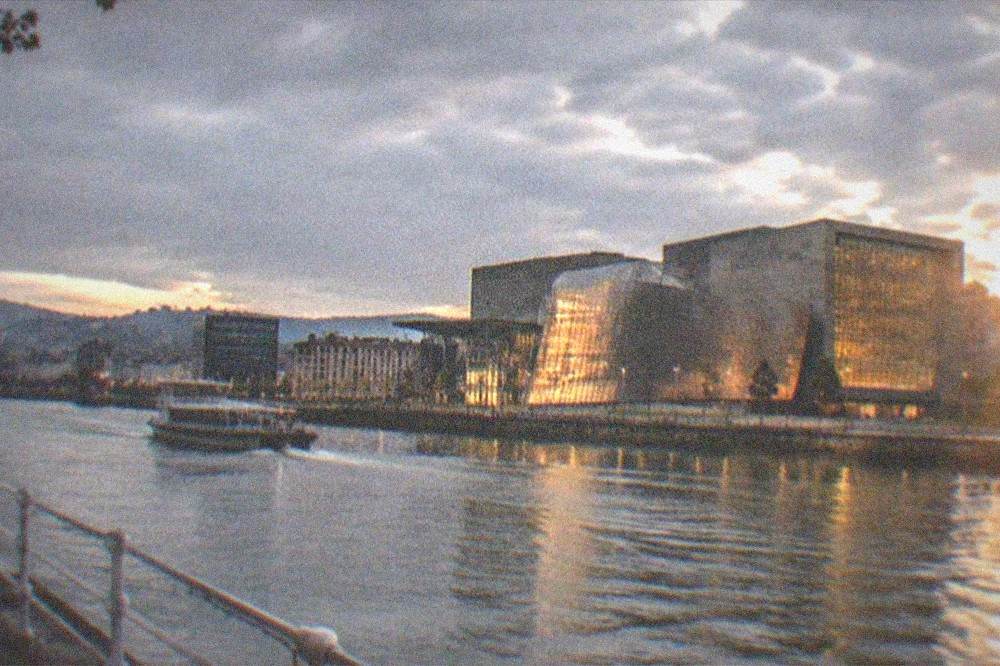 The Euskalduna Palace building illuminated at dusk with reflections on the Nervion estuary in Bilbao