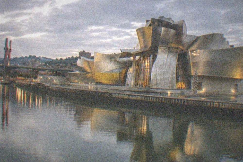 A view across the river at dusk with the illuminated museum reflected in the calm water