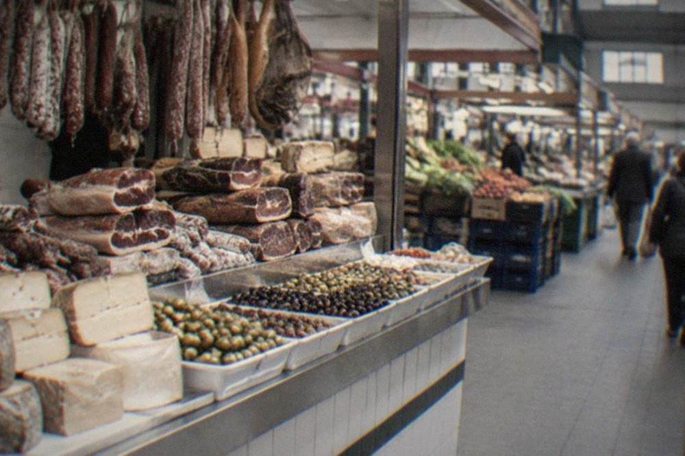 Close view of a market counter with cured meats, cheeses and olives displayed in trays