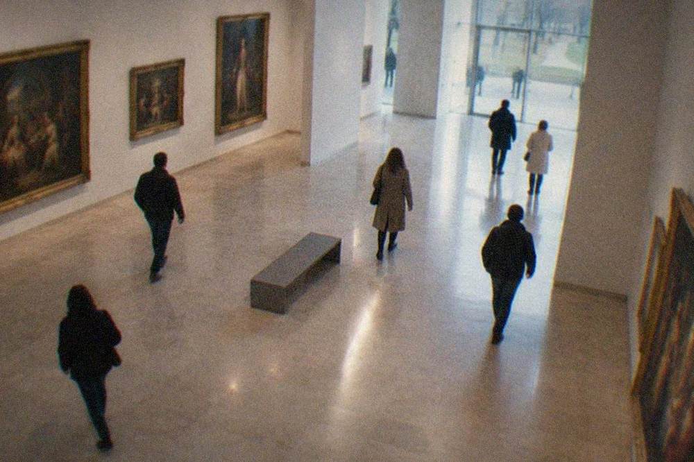 Visitors walking through a bright gallery of classical paintings in the Museum of Fine Arts Bilbao