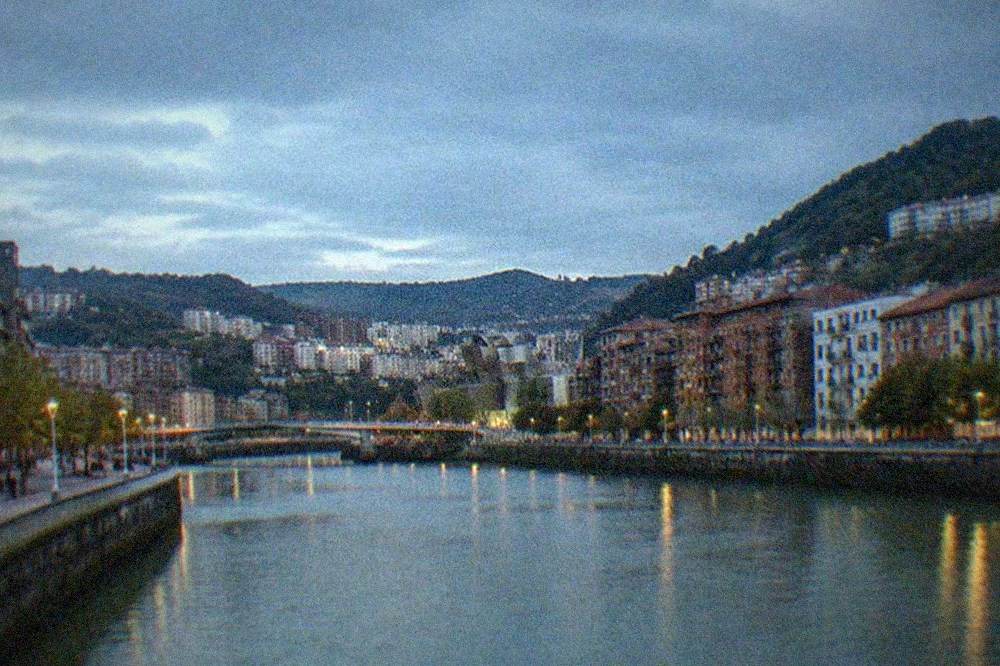 A classical oil painting of a Basque coastal scene displayed in a softly lit gallery