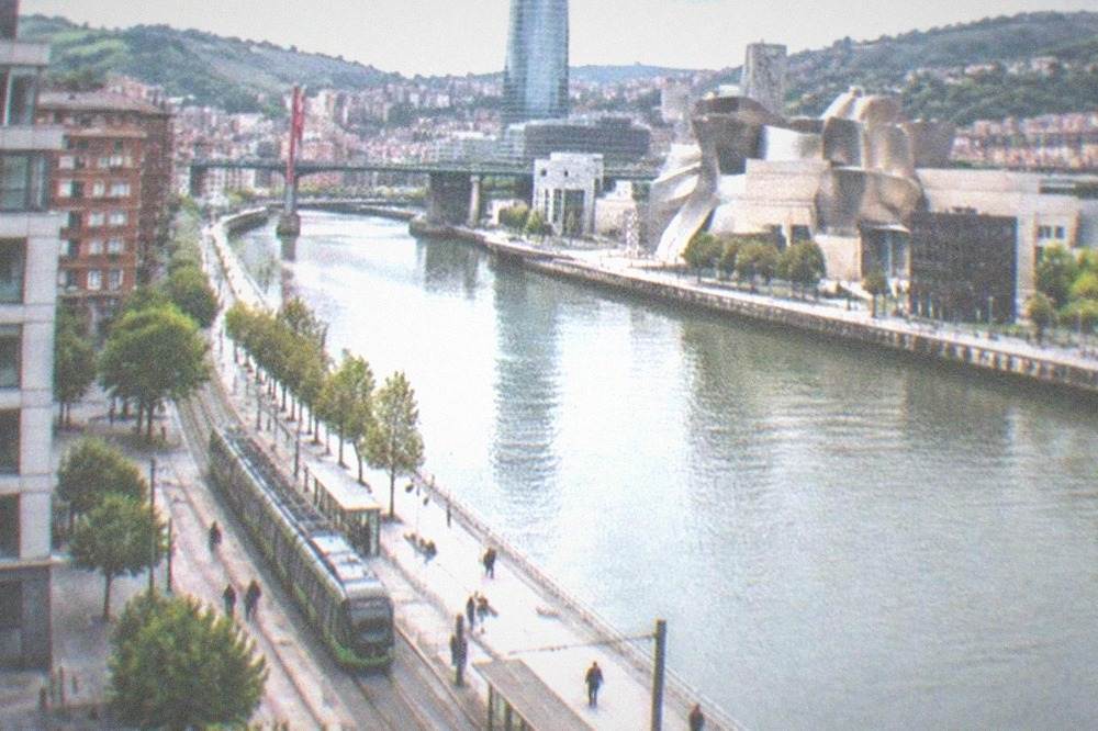 A tram passing modern buildings on the Abandoibarra riverside in Bilbao