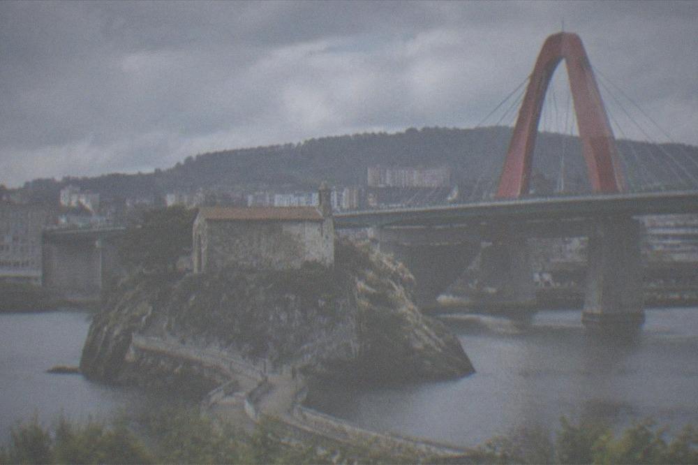 A stone hermitage on a rocky islet connected to land by a narrow winding causeway