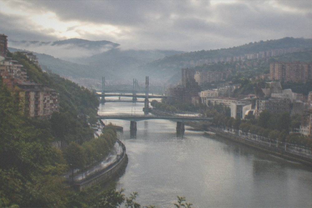 Morning mist over the Bilbao estuary with bridge silhouettes and calm grey water