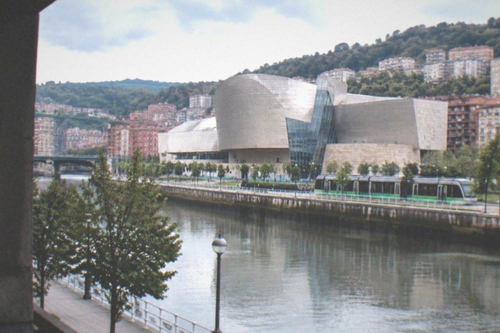 The Bilbao tram running along the riverside with the Euskalduna Palace behind it