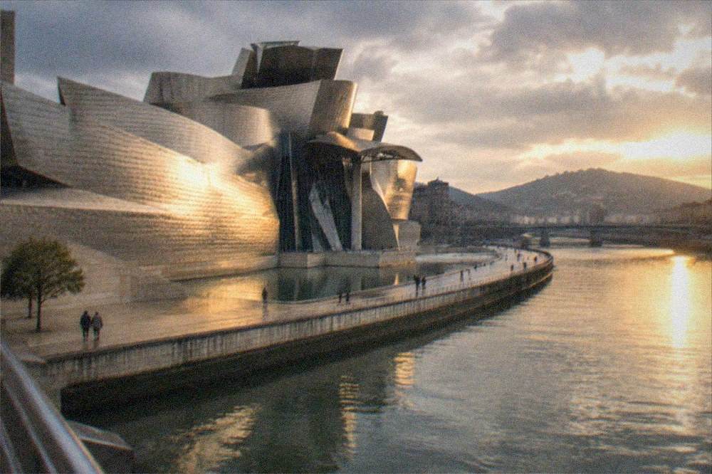 Golden evening light on the Bilbao estuary with the Guggenheim Museum glowing across the water