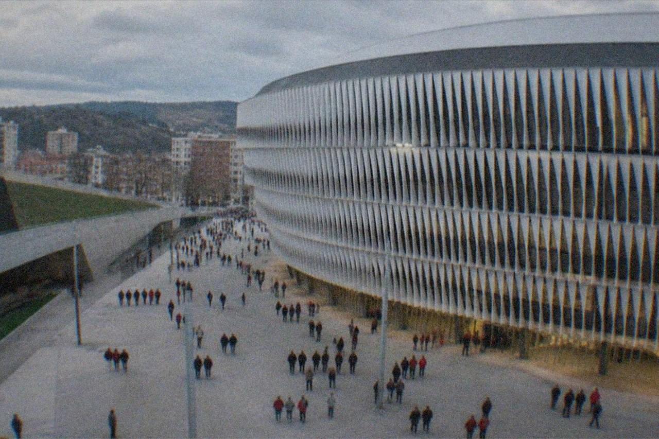 The modern facade of San Mamés Stadium in Bilbao lit in the evening with fans walking past