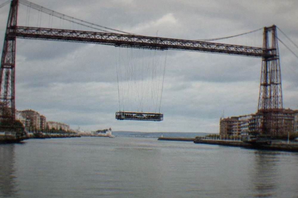 The suspended gondola of the Vizcaya Bridge carrying passengers and a car across the estuary