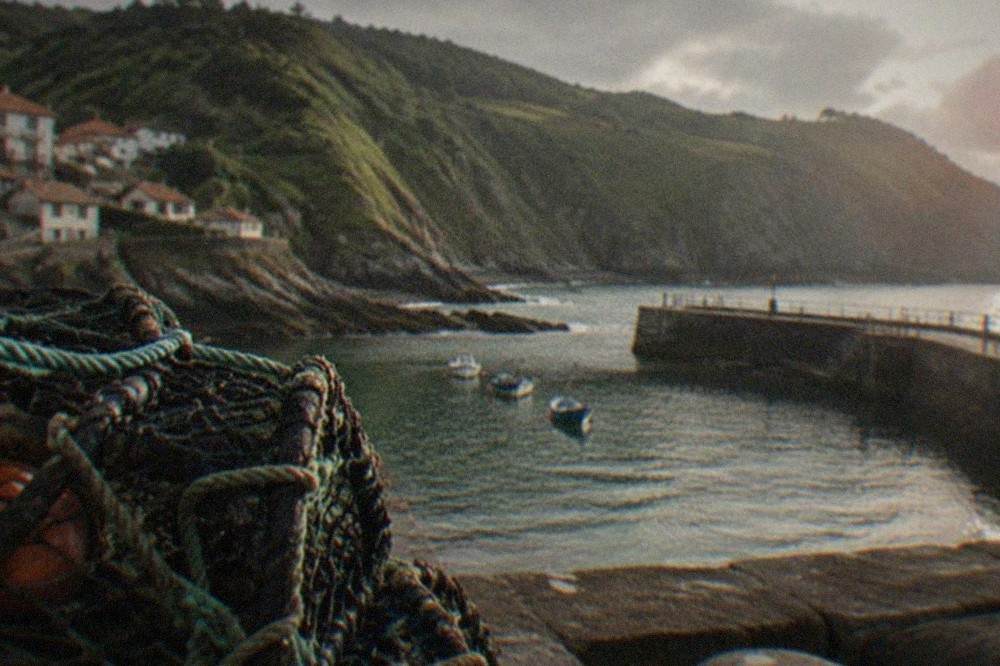 Rocky cove with clear water and green cliffs at the edge of a village