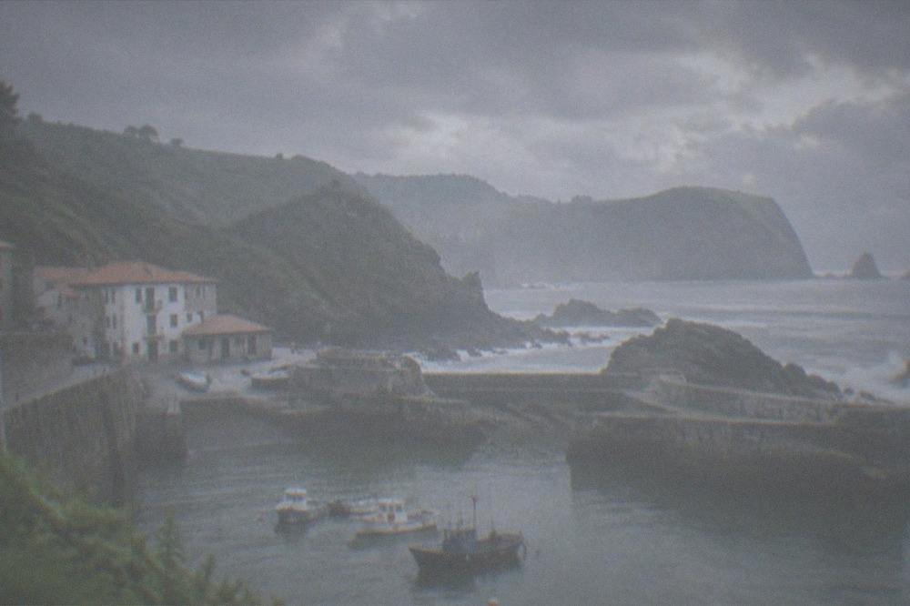 Sea crashing against dark rocks under a dramatic cloudy sky