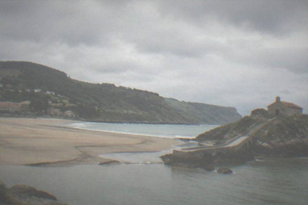 A stone hermitage on a rocky islet connected to the mainland by a narrow causeway